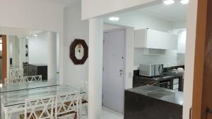 a kitchen with a glass table and white cabinets at Avelinos praia mar in Guarujá