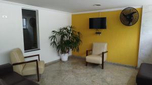 a waiting room with chairs and a tv on a yellow wall at Avelinos praia mar in Guarujá