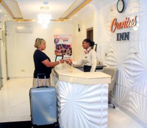 two women shaking hands at a counter in a store at Caritas Inn Lekki in Lagos