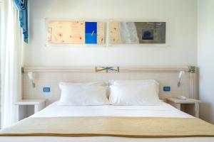 a bedroom with a bed with white sheets and pillows at Elaia Garden Hotel in Sperlonga