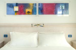 a bed with two pillows and a painting above it at Elaia Garden Hotel in Sperlonga