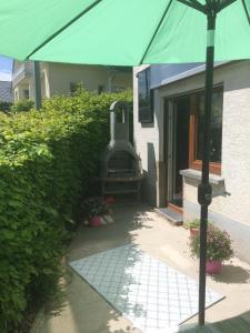 a large green umbrella in front of a house at Ferienhaus Störzel Wohnung A in Morbach