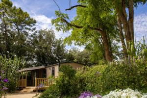 a tiny house in a garden with flowers at Camping Le Bois Verdon in Saint-Jean-de-Monts