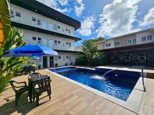 a patio with a pool and a table and umbrella at Chalés do Bona - Loft 14 in Ubatuba
