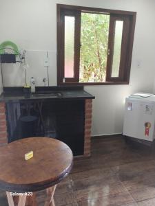 eine Küche mit einem Schreibtisch, einem Tisch und einem Fenster in der Unterkunft Morada do sabiá in Resende + 10 Fotos