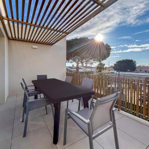 a table and chairs on a balcony with the sun at Grande Terrasse & Parking - à Vias in Vias