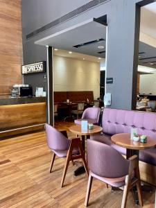 a lobby with purple chairs and tables and a couch at Flat particular incrível no hotel Interc Paulista com vaga in Sao Paulo