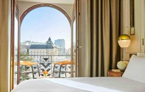 a bedroom with a bed and a view of a city at InterContinental Athenee Palace Bucharest by IHG in Bucharest