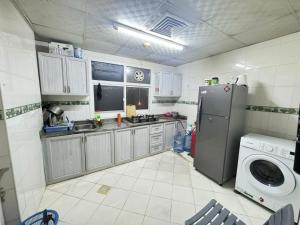 a kitchen with a refrigerator and a washing machine at Stay home in ‘Uqayr