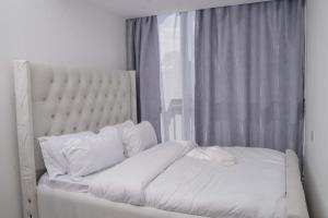 a bed with white sheets and pillows next to a window at Iconic 1Br in Riverside with views and gym in Nairobi