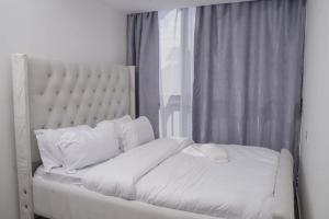 a bed with white sheets and pillows next to a window at Iconic 1Br in Riverside with views and gym in Nairobi
