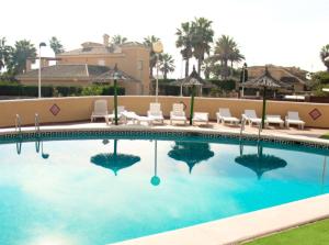 basen z krzesłami i parasolami w obiekcie Apartamentos Olympia Garden w mieście La Manga del Mar Menor