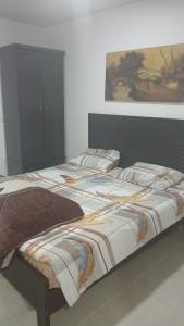 a large bed in a bedroom with a painting on the wall at La MAISON DU VAL in Jbeil