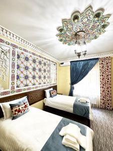 a hotel room with two beds and a chandelier at Daro Boutique in Bukhara