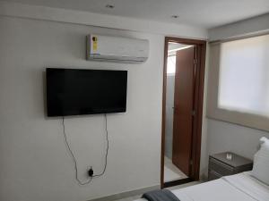 a room with a tv on a wall with a bed at Paradise Beach Flat in João Pessoa
