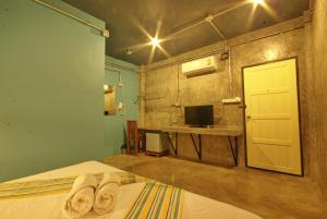 a bedroom with a bed and a door and a television at Khaolak Hostel in Khao Lak