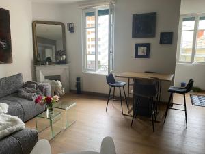 a living room with a couch and a table with chairs at Charmant appartement quartier des thermes in Vichy