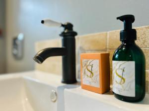 a bottle of soap sitting next to a bathroom sink at The Old Post Office - MaisonPro in Stroud +30 photos