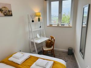 a bedroom with a bed and a desk and window at The Old Post Office - MaisonPro in Stroud