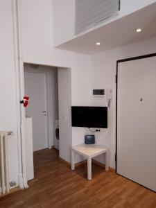 Habitación blanca con mesa y TV en la pared. en NavigliBocconi LeCase&Vacanze Ambrosiane, en Milán