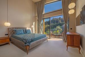 a bedroom with a bed and a large window at Vadis Luxury Villa Rhodes in Koskinou