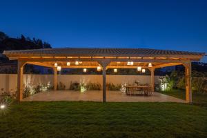 a wooden pergola with a table in a yard at Vadis Luxury Villa Rhodes in Koskinou