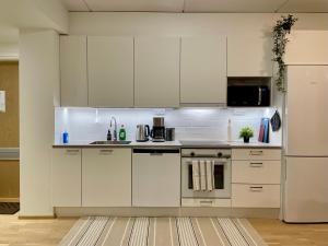 a kitchen with white cabinets and a refrigerator at Penthouse Sauna Myyrmanni in Vantaa
