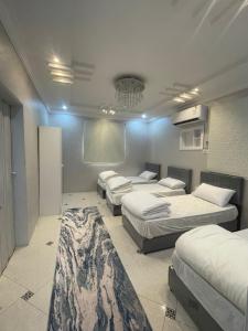 a room with four beds and a rug in it at Alfatih apartments شقق الفتح in Al Madinah