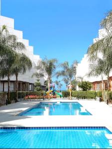 a swimming pool with palm trees and a building at Porto said بورتوسعيد شاليه غرفه وصاله للأسر فقط in `Ezbet Shalabi el-Rûdi