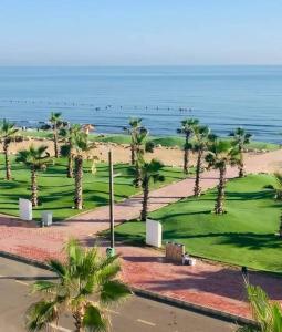 a view of a golf course with palm trees and the ocean at Porto said بورتوسعيد شاليه غرفه وصاله للأسر فقط in `Ezbet Shalabi el-Rûdi +18 photos