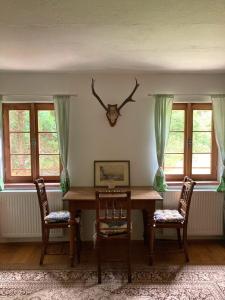 een eettafel met 2 stoelen en een hertenkop aan de muur bij Dvůr Metlice in Rožmberk nad Vltavou