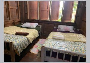 Kampong HuaibūYor Song Hostel Pai的配有窗户的客房内的两张床