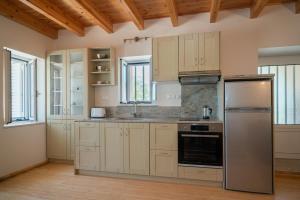 a kitchen with white cabinets and a stainless steel refrigerator at Neapolis Oasis - Lower House in Neapolis