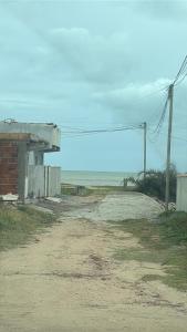 a dirt road next to a building and the ocean at Casa de temporada a 10 metros da praia in Cabo Frio