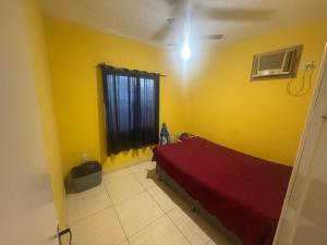 a bedroom with a red bed in a yellow wall at Casa de temporada a 10 metros da praia in Cabo Frio