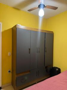 a bedroom with a large cabinet with a ceiling fan at Casa de temporada a 10 metros da praia in Cabo Frio