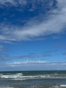 a beach with the ocean and a cloudy sky at Casa de temporada a 10 metros da praia in Cabo Frio
