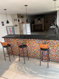 a kitchen with three bar stools and a counter at pousada ranchinho sorocaba in Sorocaba