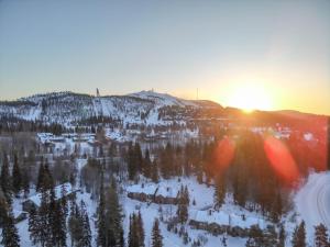 a snow covered mountain with the sun setting on the horizon at Villa Talvikolo - Spacious 2BR Cabin with Sauna in Ruka