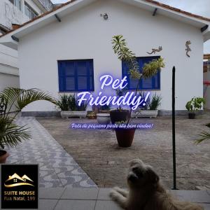 a dog standing in front of a house with a sign at Kitnets a 200 m da praia in Peruíbe