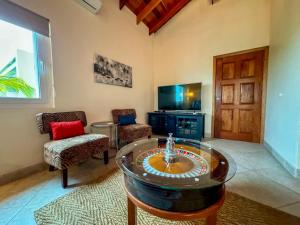 Una sala de estar con una mesa y sillas y un televisor. en La Perla Azul Beach House with Pool and 4 seater cart, en San Pedro