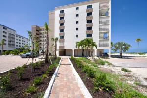 un edificio con palmeras y una pasarela de ladrillo en Pelican Watch #502 by Sun Palace Vacations, en Fort Myers Beach
