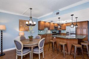 Una cocina con gabinetes de madera y una mesa y sillas. en Pelican Watch #502 by Sun Palace Vacations, en Fort Myers Beach 18 fotos más