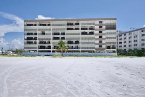 a building with a palm tree in front of a beach at Pelican Watch #503 by Sun Palace Vacations in Fort Myers Beach