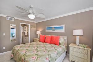 a bedroom with a bed with red pillows and a ceiling fan at Pelican Watch #503 by Sun Palace Vacations in Fort Myers Beach