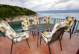 a table and chairs on a balcony with a view of the water at House Bernardica in Vrbnik