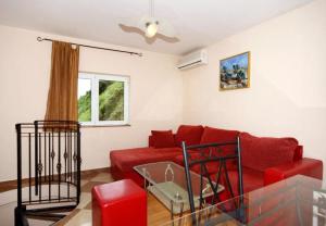 a living room with a red couch and a window at House Bernardica in Vrbnik