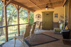 a screened in porch with chairs and a table at Boulderdash Cabin in Bandera