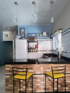a kitchen with two yellow chairs and a counter at Casa mobiliada para Cop 30 in Ananindeua