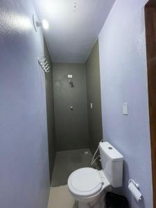 a bathroom with a white toilet in a room at Pousada Quinta das Flores in Icapuí